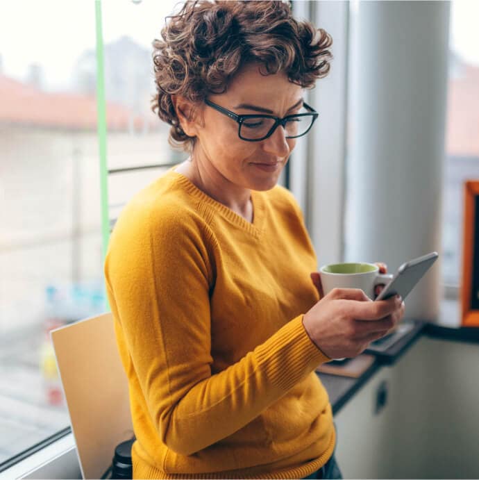 Woman holding a cup and a mobile phone