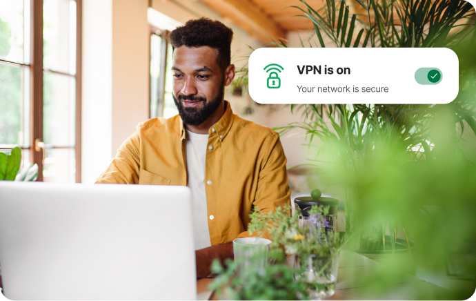 Man surrounded by plants smiling at a laptop